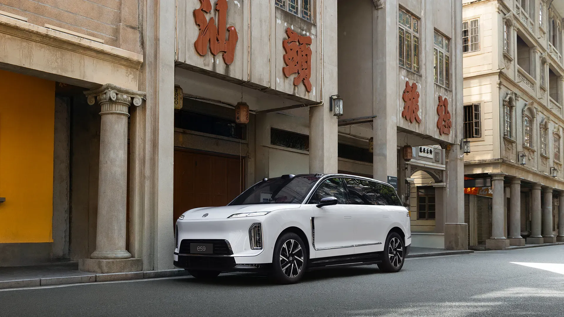White NIO ES9 in three-quarter view parked in Shantou's historic arcade district against colonial-style architecture.