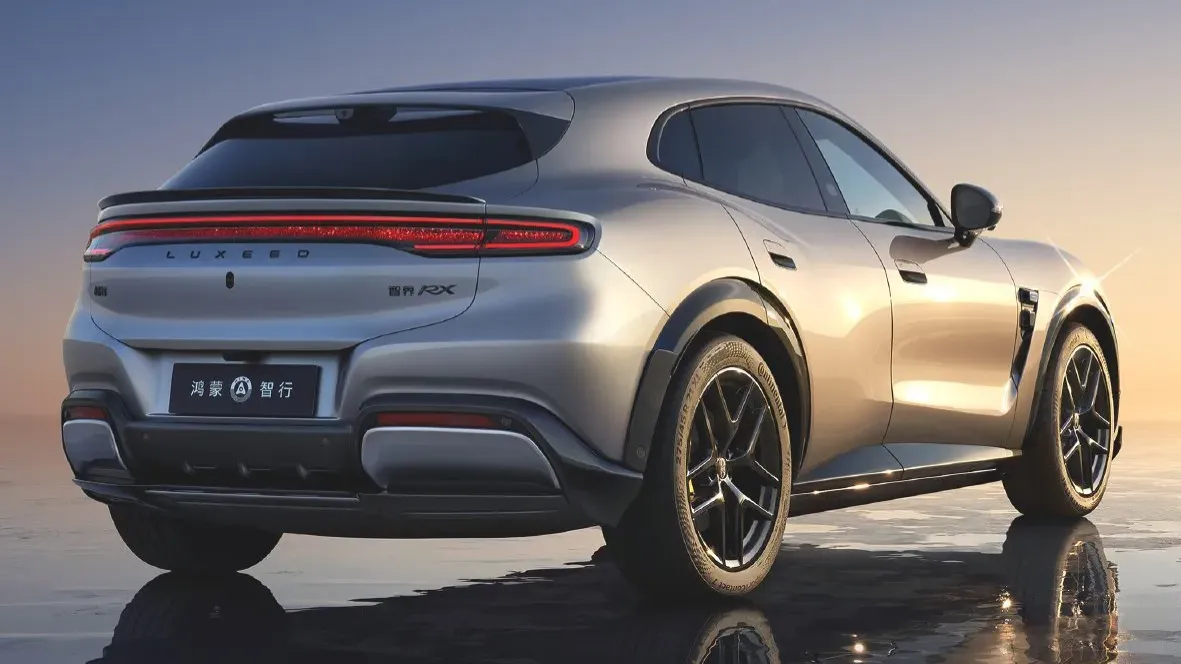 Rear three-quarter view of the silver Luxeed RX showing its full-width LED taillight bar and HIMA rear badge at dusk