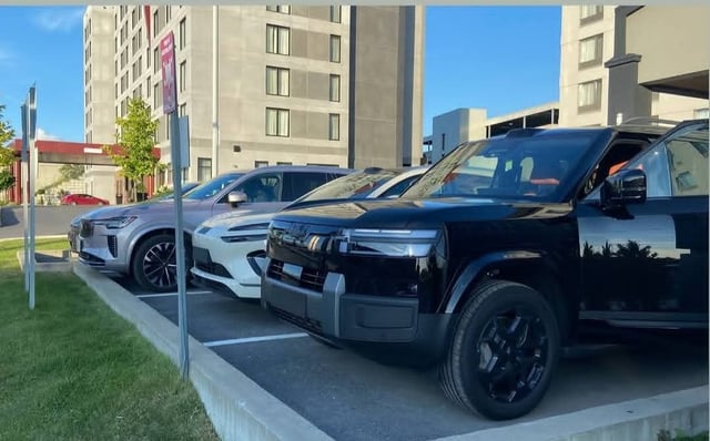A white BYD Sealion 06 EV and a black FangChengBao Bao 8 parked side by side outside a Montreal hotel