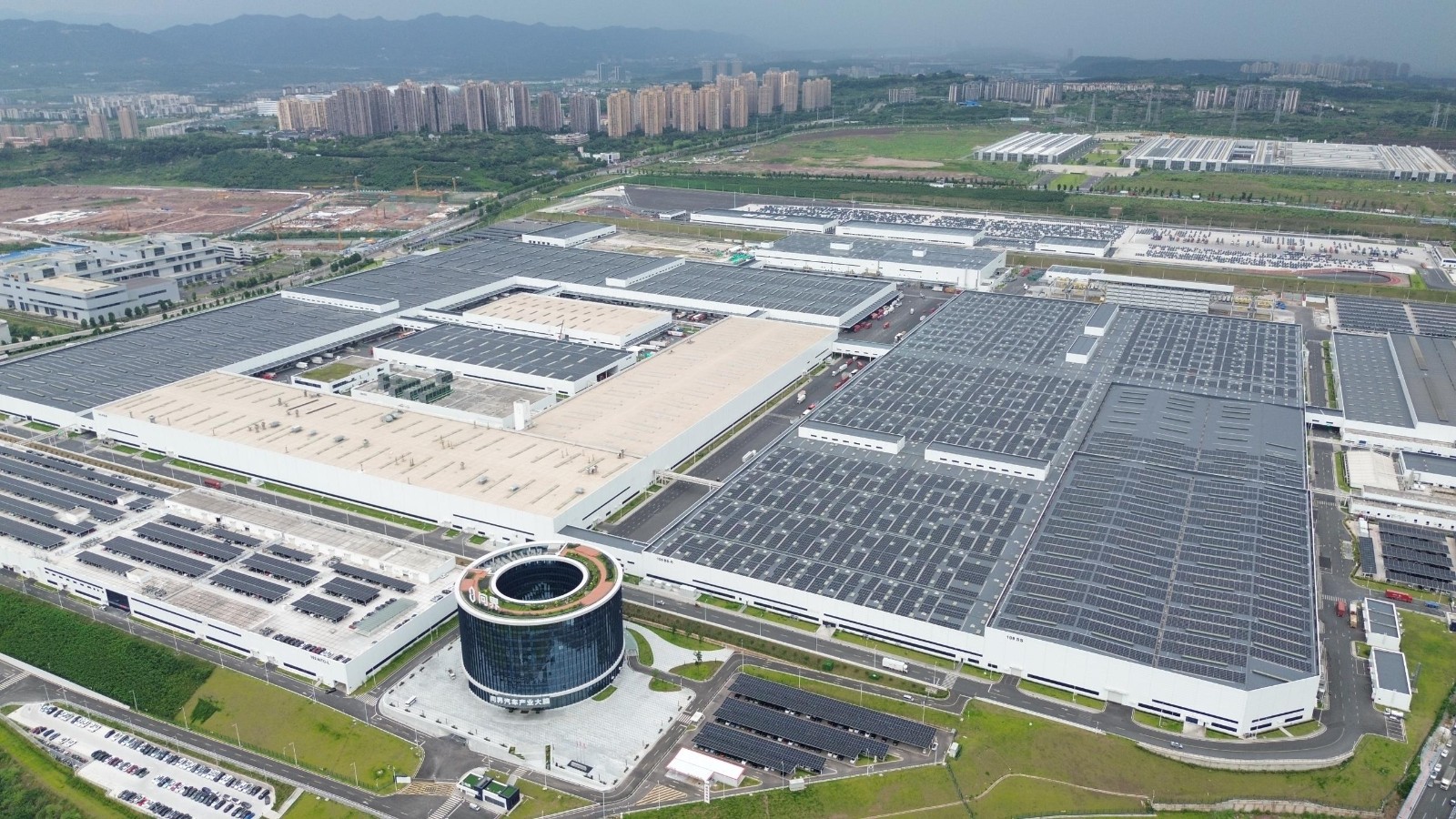 Aerial view of the SERES Super Factory in Chongqing, with solar panels across its roofs and a round glass building