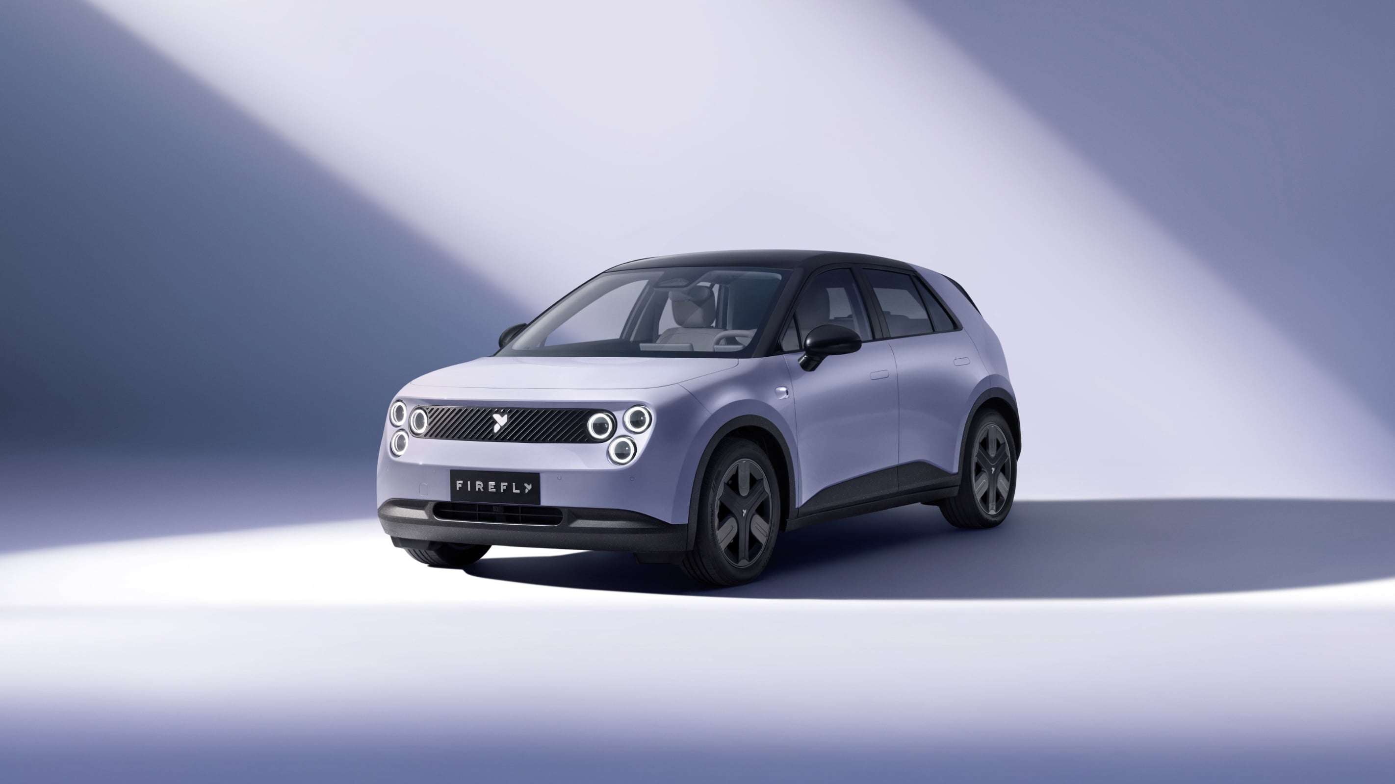 Lavender Firefly compact electric hatchback seen from the front three-quarter under a studio spotlight
