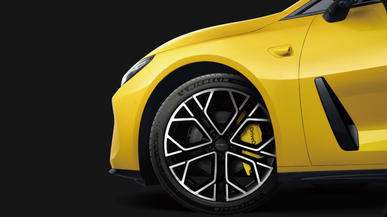 Front wheel of a yellow GAC Aion Ray 7 with a yellow Huawei DriveONE brake caliper behind black and silver spokes