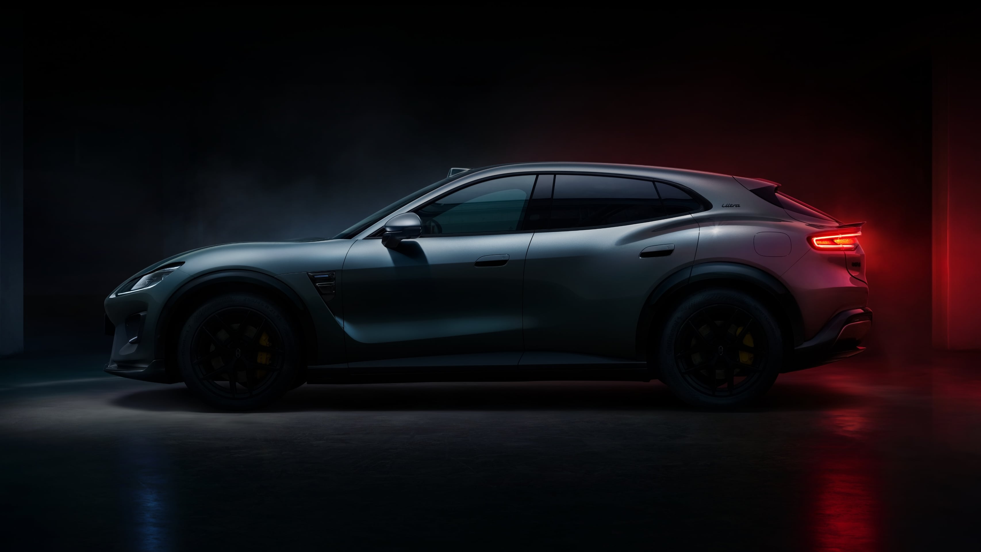 Dark grey Luxeed RX coupe SUV in side profile against a dark studio backdrop, with yellow brake calipers behind black wheels