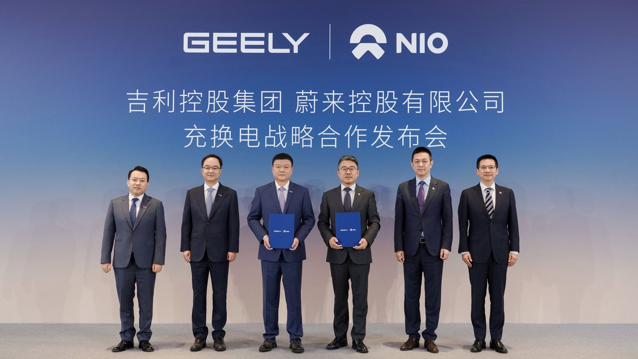 NIO and Geely Holding executives hold signed agreement folders at the charging and swapping partnership event