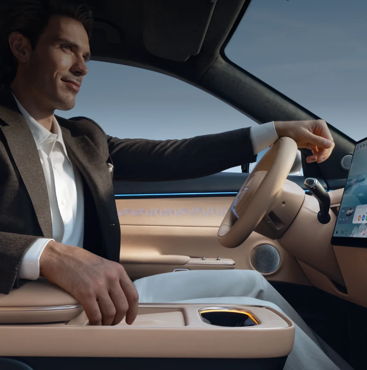 Driver in a tweed jacket at the wheel of an Omoda and Jaecoo SUV with a beige leather cabin, floating console and touchscreen
