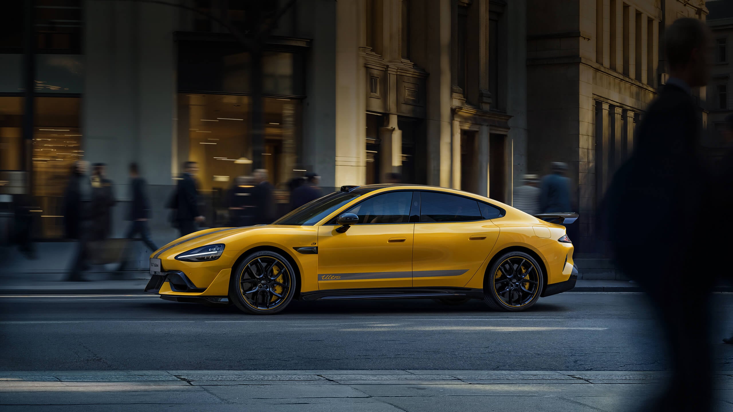 Yellow Xiaomi SU7 Ultra sedan in side profile on a city street with pedestrians blurred in motion behind it