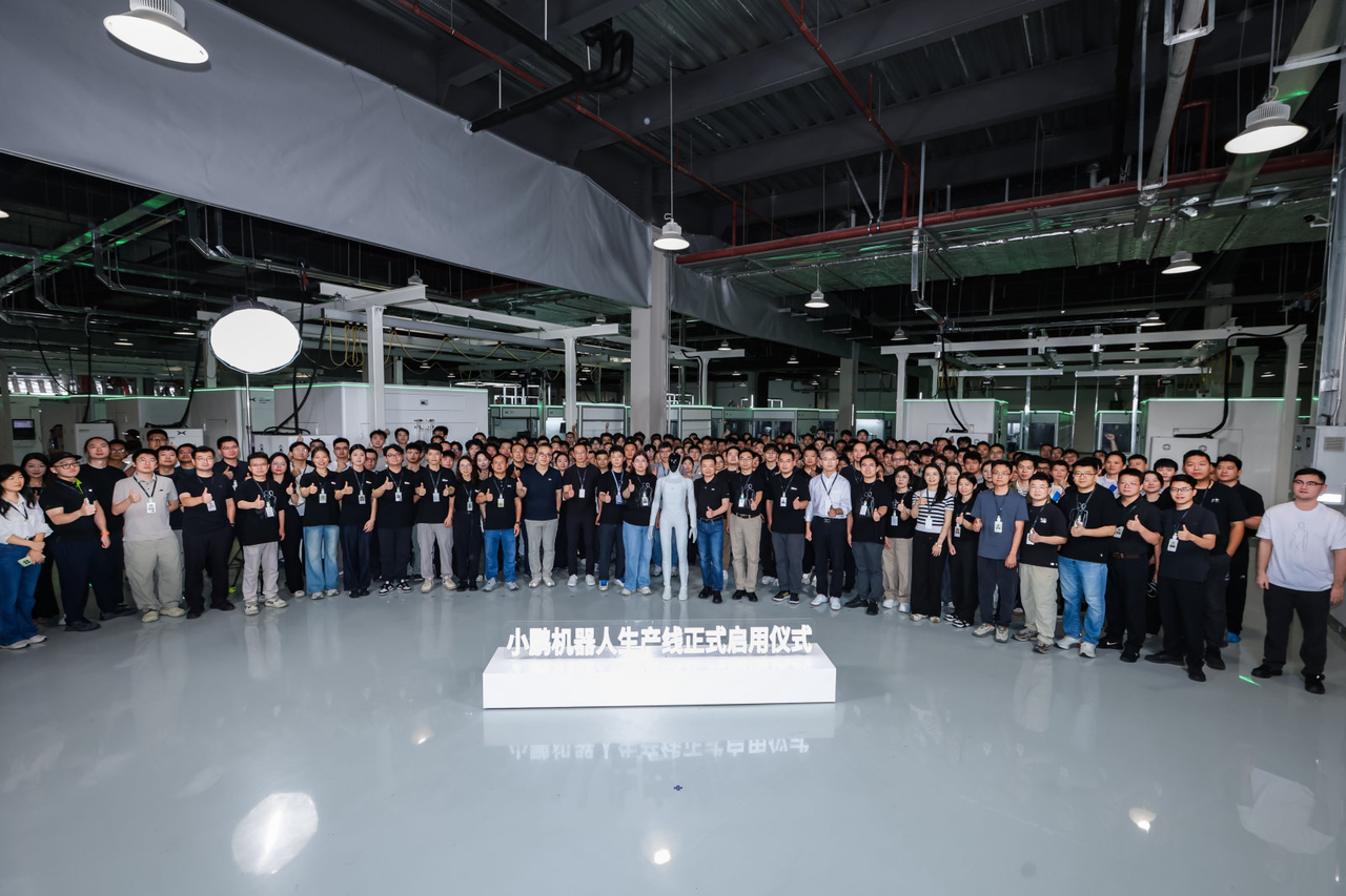 Crowd of XPeng employees and the IRON humanoid robot at the ceremony marking the robot's production line launch.