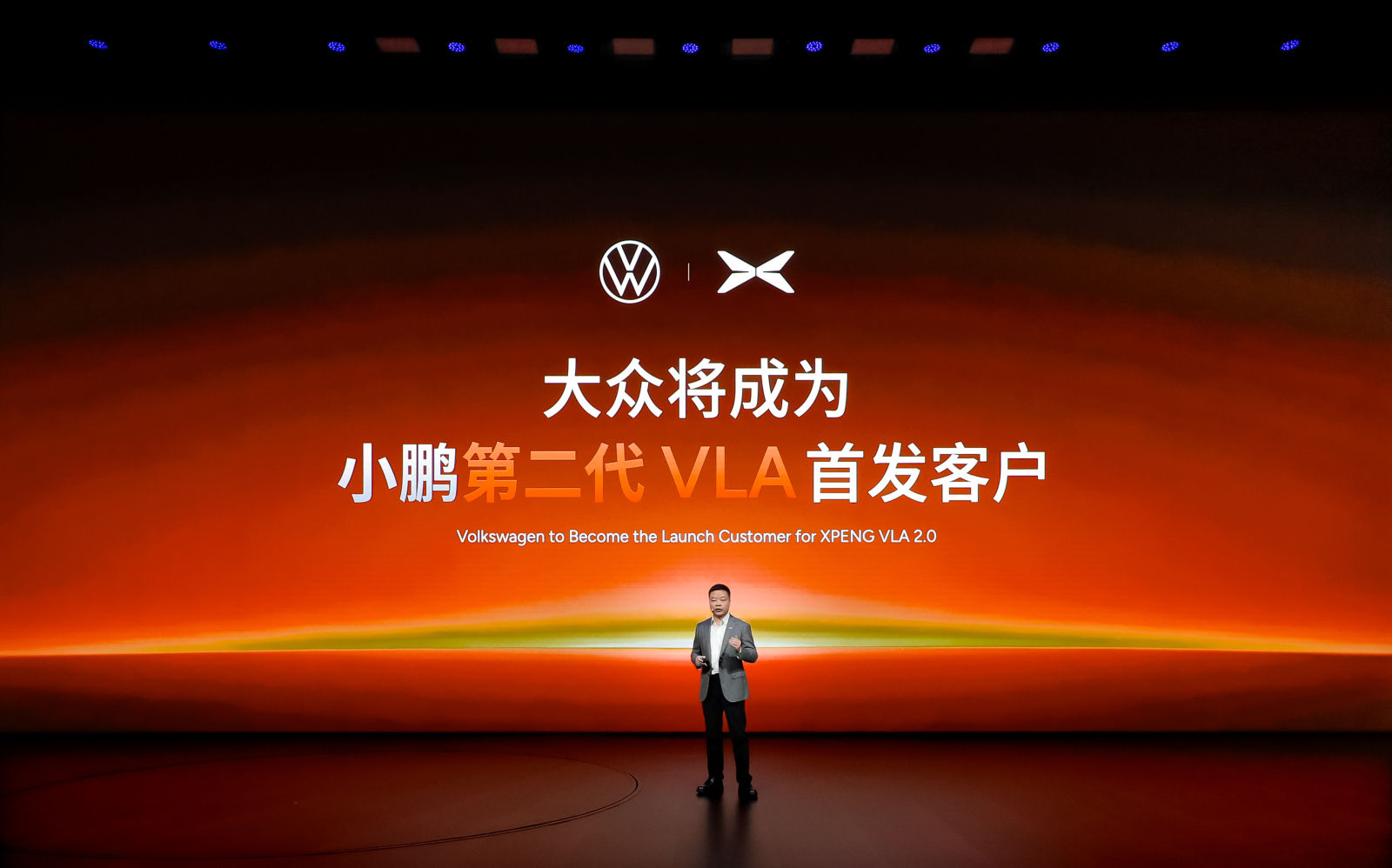 XPeng CEO He Xiaopeng on stage announcing Volkswagen as the launch customer for XPeng's VLA 2.0 driving system.
